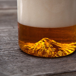 Amigos lançam copo de cerveja feita a mão com detalhes de montanha